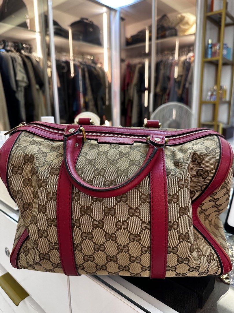 Gucci Monogram Canvas Red Leather Trim Boston Bag (Category: Luxury Bags & Wallets) located in Santo Domingo. Submitted by itznyxi3 (Listing ID 1443834185, Image 1). Description: - Authentic Gucci Boston Bag - Classic GG Monogram Canvas - Red Leather Trim and Handles - Zip Top Closure - Interior Zip Pocket and Slip Pockets - Detachable Shoulder Strap Included - Great for Everyday Essentials - Shows some signs of wear (inside and out), but has ple