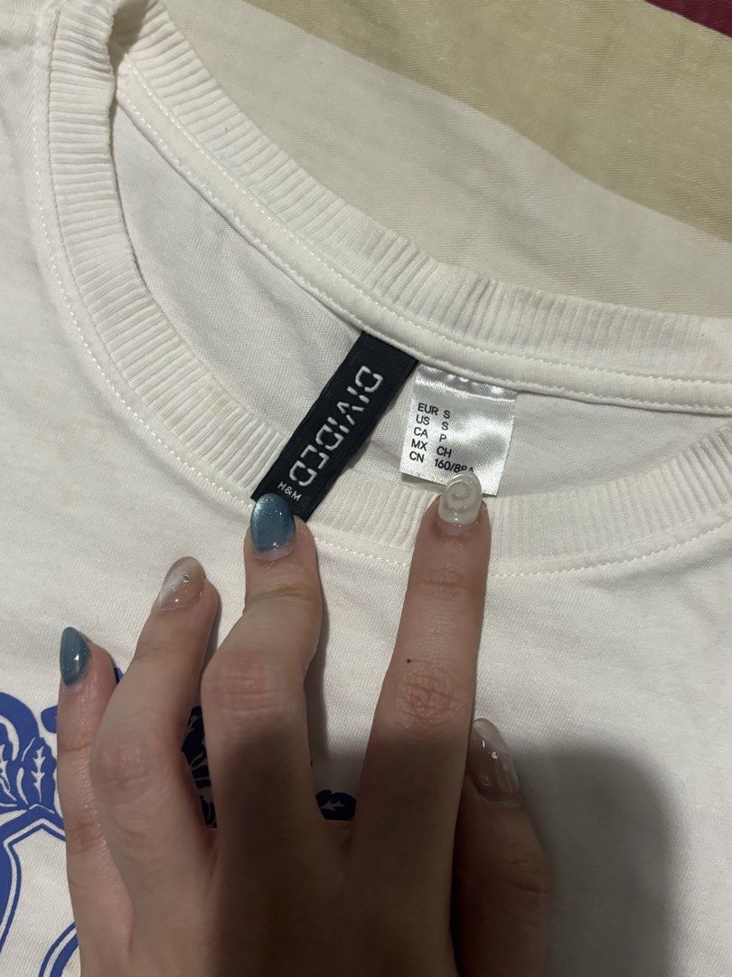H&M Divided White Cropped T-shirt with Blue Crest Graphic (Category: Shirts) located in Bauan. Submitted by danadtngn (Listing ID 1443825708, Image 2). Description: Last used back in 2019. A bit yellowish from being kept in the closet for too long but still pretty, just needs some laundry. .