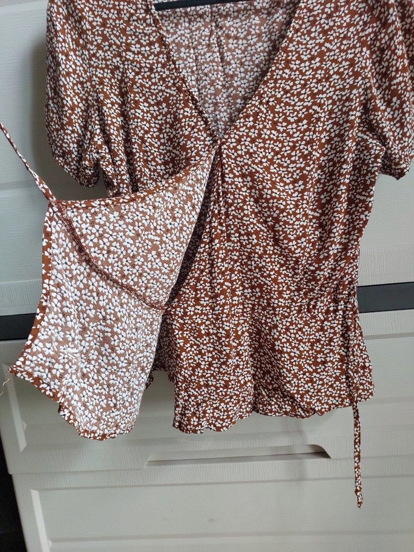 Mango Brown Floral Wrap-around Peplum Top (Category: Blouses) located in Pasay City. Submitted by mcleo10 (Listing ID 1443768167, Image 2). Description: - Adorable brown top with a charming ditsy floral print. - Features stylish puff sleeves for a feminine touch. - Adjustable tie details on both sides for a customized fit. - Made from a light and flowy fabric, ensuring comfort. - Versatile piece, ideal for casual outings or dressing up for a nigh