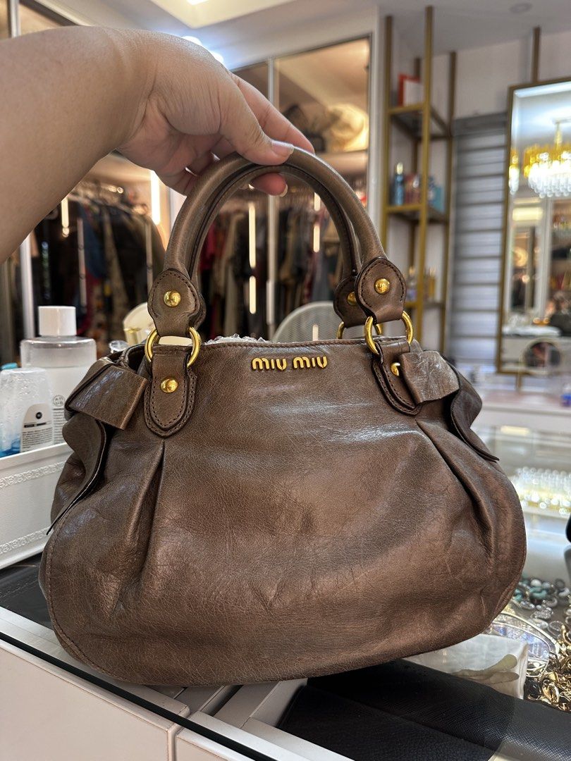 Miu Miu Bow bag leather handbag (Category: Luxury Bags & Wallets) located in Santo Domingo. Submitted by itznyxi3 (Listing ID 1443768408, Image 2). Description: - Authentic Miu Miu bag - Material: Leather - Design: Gathered - Hardware: Gold - Interior: Zip pocket, main compartment - Features: Comfortable handles - Ideal for: Everyday use.