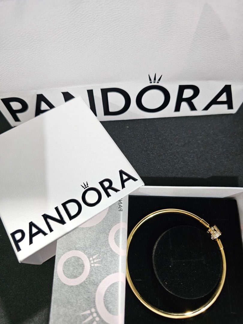 Pandora Gold Finish Bangle Bracelet with Clasp (Category: Bracelets) located in Pasig City. Submitted by qratesandqarts (Listing ID 1443788452, Image 2). Description: - Authentic Pandora bangle bracelet -Size 19cm - Elegant gold-tone finish - Clasp adorned with small stones - Comes with original Pandora box and paper bag - Versatile for stacking or standalone styling - A timeless Pandora classic.