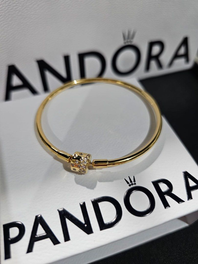 Pandora Gold Finish Bangle Bracelet with Clasp (Category: Bracelets) located in Pasig City. Submitted by qratesandqarts (Listing ID 1443788452, Image 1). Description: - Authentic Pandora bangle bracelet -Size 19cm - Elegant gold-tone finish - Clasp adorned with small stones - Comes with original Pandora box and paper bag - Versatile for stacking or standalone styling - A timeless Pandora classic.