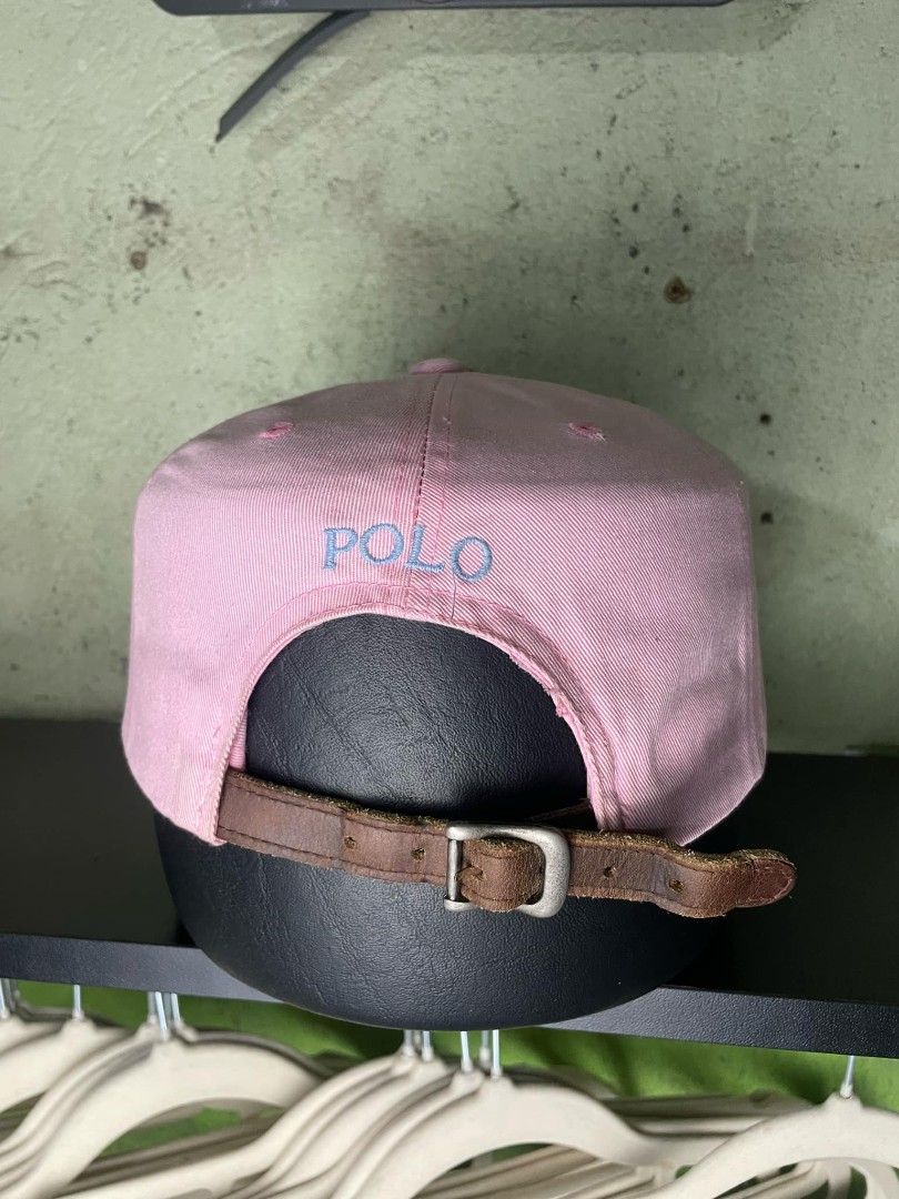 Pink Polo Ralph Lauren Cap with Leather Strap (Category: Caps & Hats) located in Ligao. Submitted by merjudioma64633 (Listing ID 1443745519, Image 2). Description: - Pink Polo Ralph Lauren cap - Iconic light blue embroidered polo player logo on front - 'POLO' embroidered on the back - Adjustable leather strap with buckle closure - Perfect for casual everyday wear - Shows some signs of wear on the strap and inside lining.