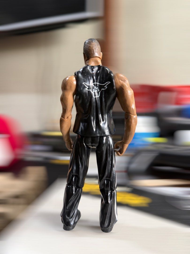 WWE Jakks The Rock Figure (Category: Action & Battle Toys) located in Mandaluyong City. Submitted by joshlim (Listing ID 1443806946, Image 2). Description: Poseable action figure of The Rock. Features his iconic 'JUST BRING IT!' tank top, black pants with white stripes, and a bull logo on the back. Perfect for wrestling fans!.