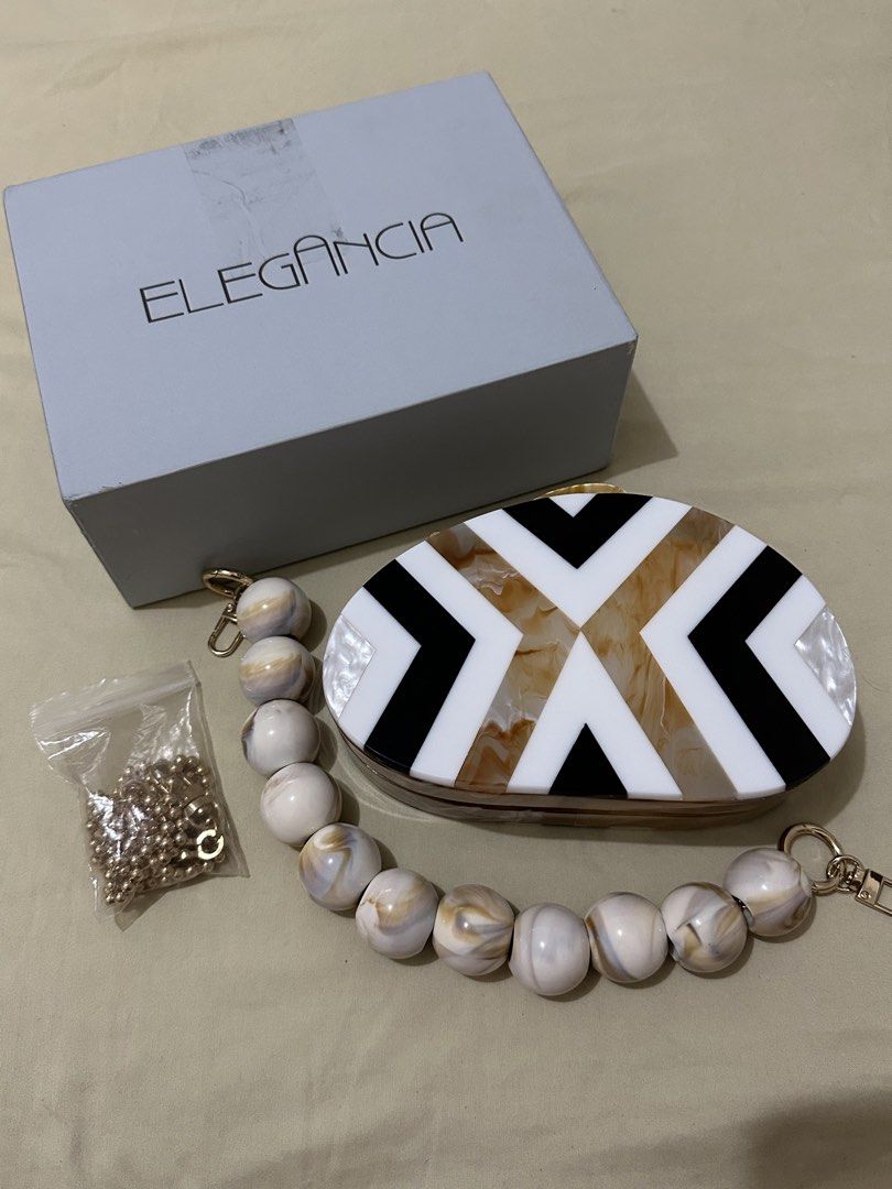 Elegancia 2-way Clutch Bag (Category: Clutches) located in Makati City. Submitted by aamii29 (Listing ID 1443970009, Image 2). Description: - Unique oval acrylic clutch - Eye-catching geometric pattern in brown, black, and white - Comes with a detachable beaded handle - Includes a versatile gold chain strap - Ideal for parties, events, or special occasions - Bought for ₱1,500. Selling for ₱800 - RFS: Decluttering.