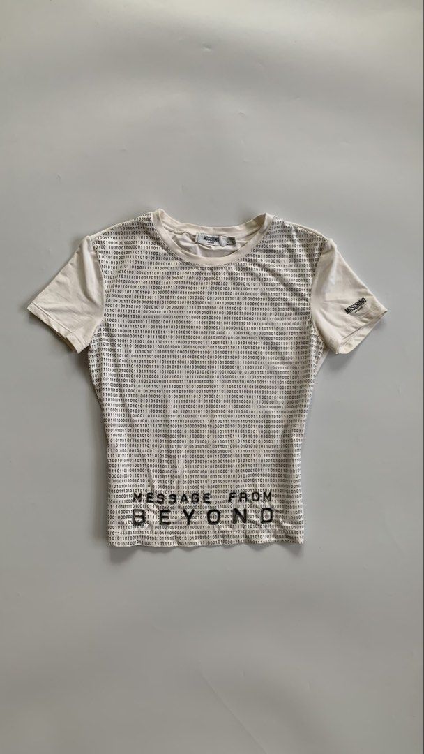 Moschino graphic baby tee (Category: Shirts) located in Tarlac. Submitted by luv__vintage (Listing ID 1443918727, Image 3). Description: - White short-sleeved t-shirt - Unique all-over binary code graphic print on the front - Features 'MESSAGE FROM BEYOND' text in black below the print - Estimated size: Small to Medium - Ideal for a casual and edgy style.