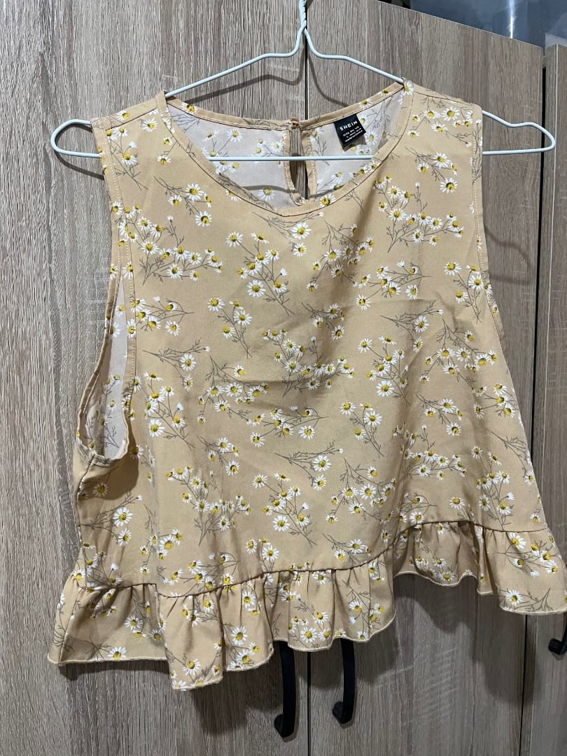 SHEIN Daisy Print Cropped Top with Ruffle Hem (Category: Blouses) located in Cabanatuan. Submitted by declutteringhaven (Listing ID 1443933450, Image 1). Description: - Cute cropped top from SHEIN - Size: L - Color: Tan with daisy print - Design: Sleeveless with ruffled hem - Closure: Keyhole at the back - Style tip: Pairs well with jeans.
