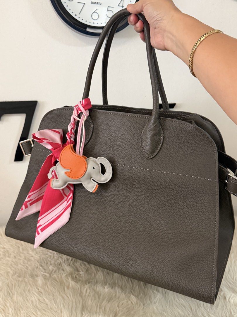 The ROW bag by Things Remembered (Category: Tote Bags) located in Mandaluyong City. Submitted by pheewz07 (Listing ID 1443916613, Image 1). Description: Things remembered THE ROW bag in silver hardware. - Hand stitched in size 15 Height: 27.5 cm (11”) Length: 39 cm (15.5”) Width: 22 cm (8.5”) Handle Drop: 40 cm (15.5”) - Smooth genuine cowhide leather - Comes with a charming elephant charm. - Adorned with a pink and red scarf tied to the handle. 