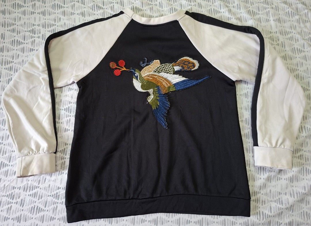 Black Raglan Sweatshirt with Embroidered Bird Design (Category: Longsleeves) located in Taytay. Submitted by marlonbeech (Listing ID 1444160627, Image 2). Description: - Black sweatshirt with contrasting cream raglan sleeves - Features a vibrant, colorful embroidered bird design on the front - Ribbed cuffs and hem for a snug fit - Comfortable and stylish, ideal for everyday casual wear. -For the specific embroidered pheasant sweatshirt in the ima