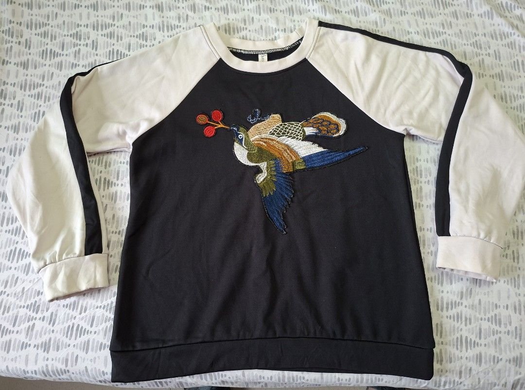 Black Raglan Sweatshirt with Embroidered Bird Design (Category: Longsleeves) located in Taytay. Submitted by marlonbeech (Listing ID 1444160627, Image 1). Description: - Black sweatshirt with contrasting cream raglan sleeves - Features a vibrant, colorful embroidered bird design on the front - Ribbed cuffs and hem for a snug fit - Comfortable and stylish, ideal for everyday casual wear. -For the specific embroidered pheasant sweatshirt in the ima