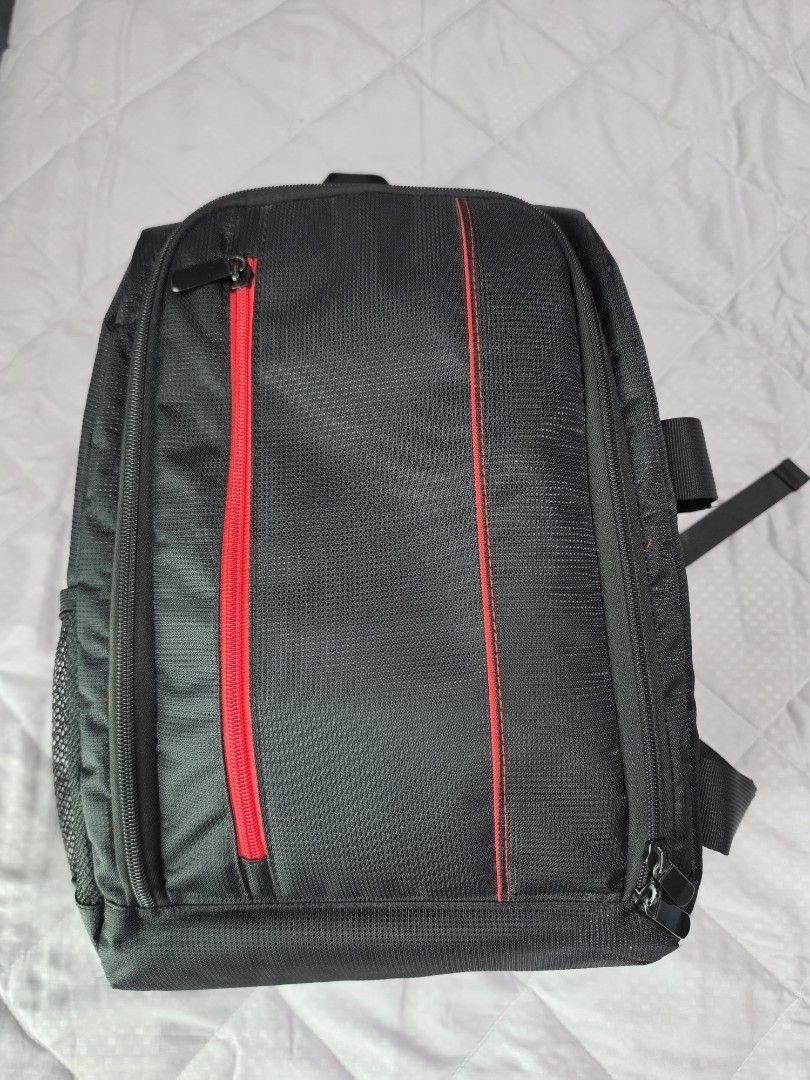 Camera Backpack (Category: Camera Bags & Carriers) located in Singapore. Submitted by sapfo (Listing ID 1444248624, Image 1). Description: - Stylish black camera backpack with eye-catching red accents. - Multiple zippered compartments to keep your camera and accessories organized. - Made from durable fabric for long-lasting use. - Top-attached straps for comfortable carrying. - Perfect for storing and transporting your camera staff..