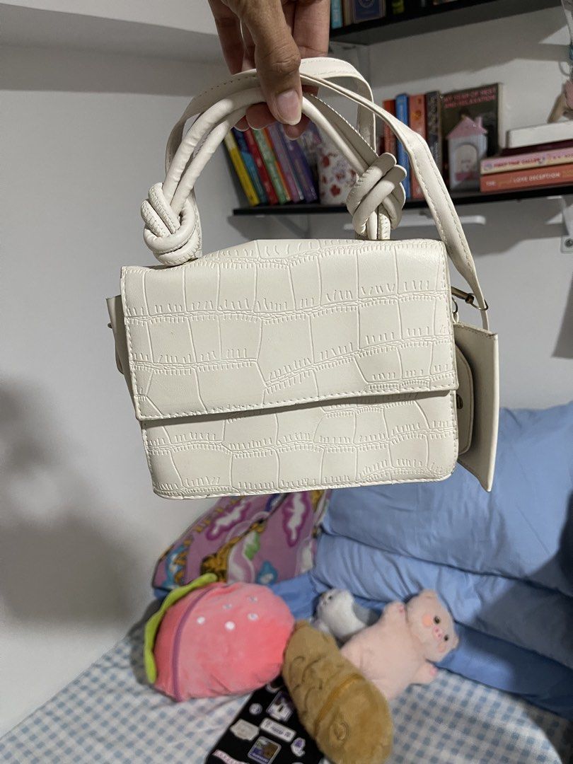 Cream Textured Knot Handle Shoulder Bag (Category: Shoulder Bags) located in Mandaluyong City. Submitted by ynsbf (Listing ID 1444247258, Image 2). Description: - Elegant cream-colored shoulder bag - Unique textured crocodile-like pattern - Stylish knot detail on top handles - Includes a long, adjustable strap for versatility - Secure front flap closure - Ideal for casual outings or dressing up your outfit - Perfectly fits your essentials: phone,