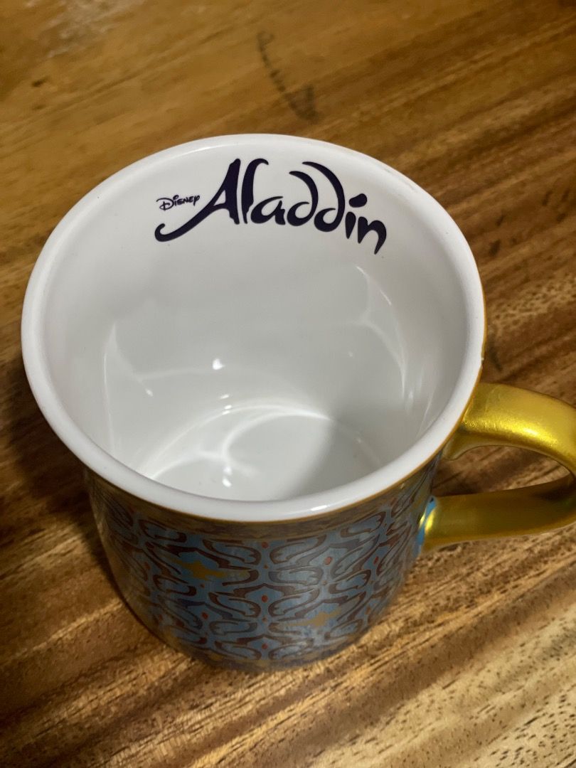 Disney Aladdin Ceramic Mug Gold Handle (Category: Coffee & Tea Tableware) located in Paranaque City. Submitted by cngaya (Listing ID 1444196484, Image 2). Description: - Authentic Aladdin mug - Bought in Sydney Australia when the Aladdin play was showing - Features a beautiful blue and gold pattern - Elegant gold handle - 'Aladdin' text in blue inside the mug - Made in China - IMPORTANT: Not safe for dishwasher or microwave (hand wash recommended