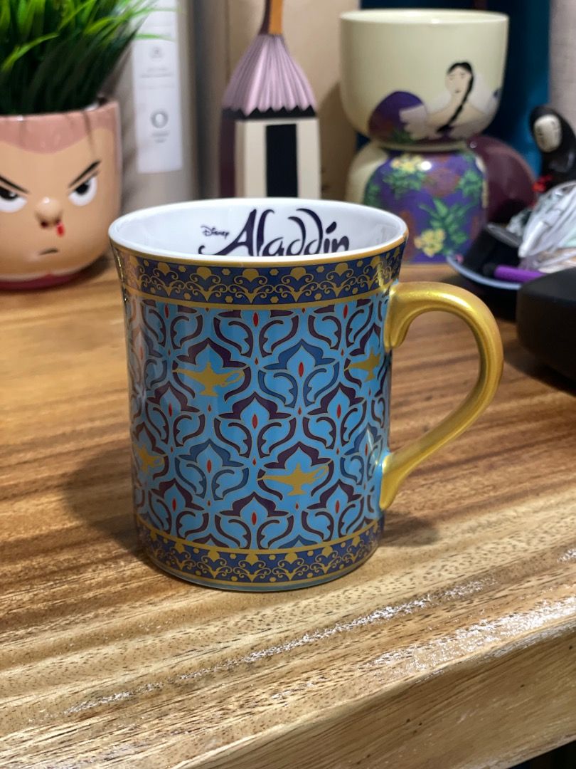 Disney Aladdin Ceramic Mug Gold Handle (Category: Coffee & Tea Tableware) located in Paranaque City. Submitted by cngaya (Listing ID 1444196484, Image 1). Description: - Authentic Aladdin mug - Bought in Sydney Australia when the Aladdin play was showing - Features a beautiful blue and gold pattern - Elegant gold handle - 'Aladdin' text in blue inside the mug - Made in China - IMPORTANT: Not safe for dishwasher or microwave (hand wash recommended