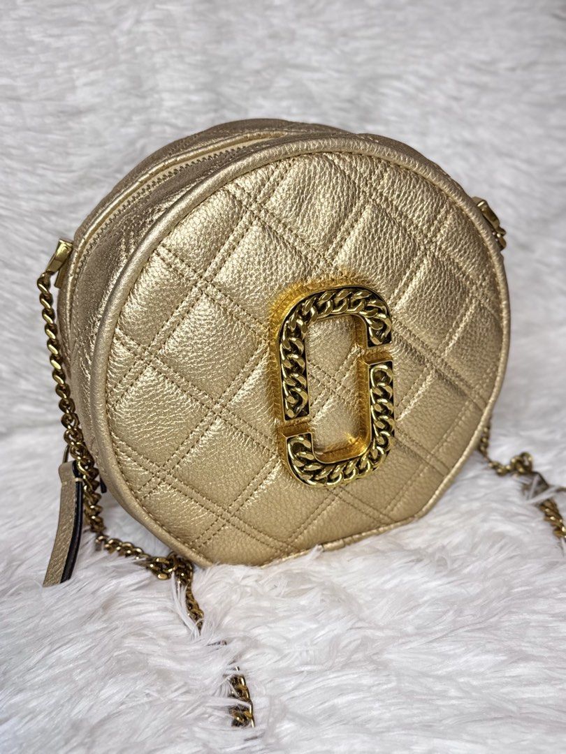 Marc Jacobs The Status Round Crossbody Bag (Category: Luxury Bags & Wallets) located in Cabuyao City. Submitted by velvetbelleph (Listing ID 1444300697, Image 2). Description: Elegant Marc Jacobs The Status Round Crossbody Bag featuring a quilted round silhouette and the signature oversized Double J logo with chain detailing. The neutral metallic beige/champagne color and antique gold-tone hardware make it easy to pair with both casual and dressy