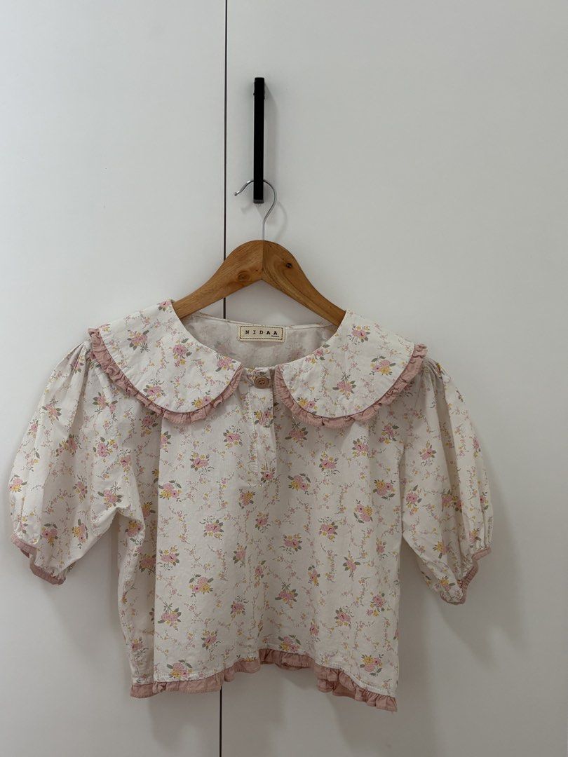 NIDAA Floral Peter Pan Collar Puff Sleeve Top (Category: Blouses) located in Bacoor. Submitted by pretticel (Listing ID 1444140582, Image 1). Description: - Cream top with charming pink floral print - Features a large, ruffled Peter Pan collar - Sweet puff sleeves for a feminine touch - Easy button-front closure - Flattering ruffled hemline - Perfect for a vintage-inspired outfit.