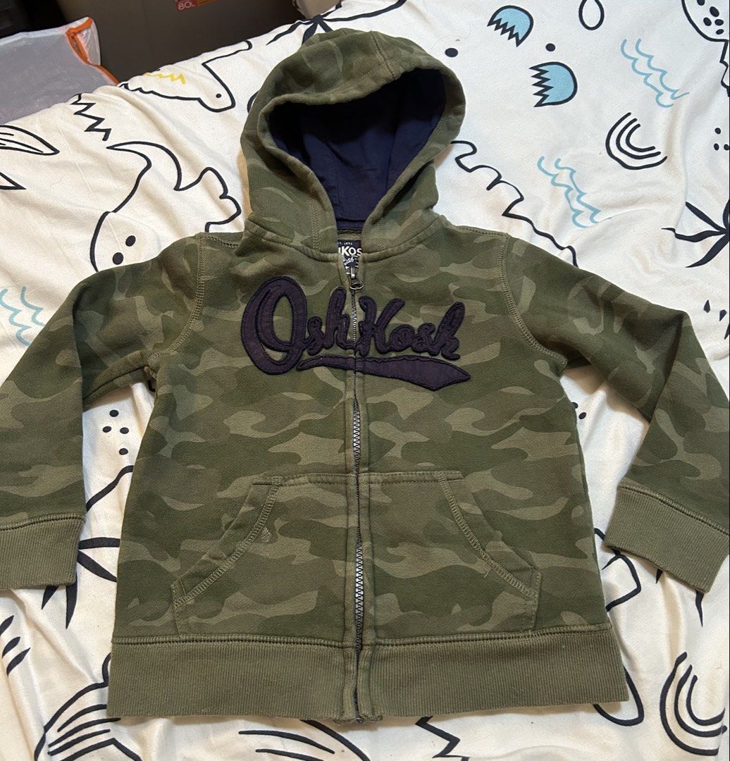 OshKosh Camouflage Jacket Hoodie, 4y (Category: Babies & Kids Fashion) located in Paranaque City. Submitted by allthatclutterph (Listing ID 1444176702, Image 1). Description: - OshKosh camo zip-up hoodie (Size 4) with navy lined hood Very good condition as seldom used.
