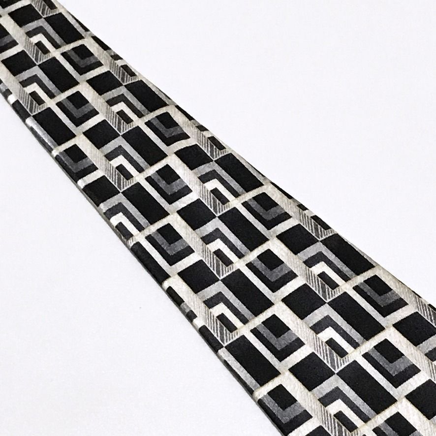 Pierre Cardin Black Geometric Neck Tie (Category: Ties) located in Taguig. Submitted by retrogaze (Listing ID 1444285760, Image 3). Description: This striking vintage necktie by Pierre Cardin masterfully embodies a retro-modernist, architectural aesthetic. This 100% silk accessory relies on a deep, black base that grounds the bold design. The fabric boasts a subtle textured quality that interacts beautifully with the light, granting the blade an 