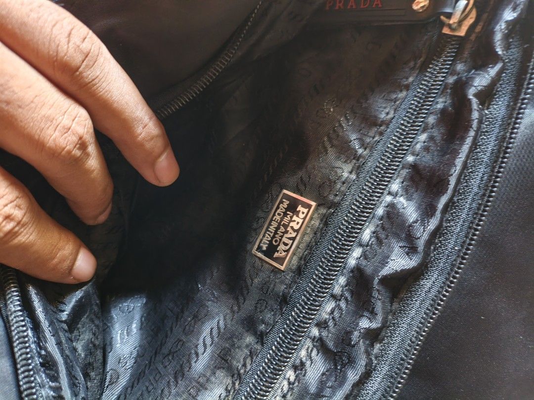 Prada Nylon Messenger Bag Black (Category: Luxury Bags & Wallets) located in Bambang. Submitted by acpalthrifts (Listing ID 1444114568, Image 3). Description: - Prada messenger bag - Black nylon material - Adjustable strap with Prada branding - Interior Prada Milano Made in Italy tag - Minor exterior wear on fabric and corners - Still functional and stylish for everyday use.