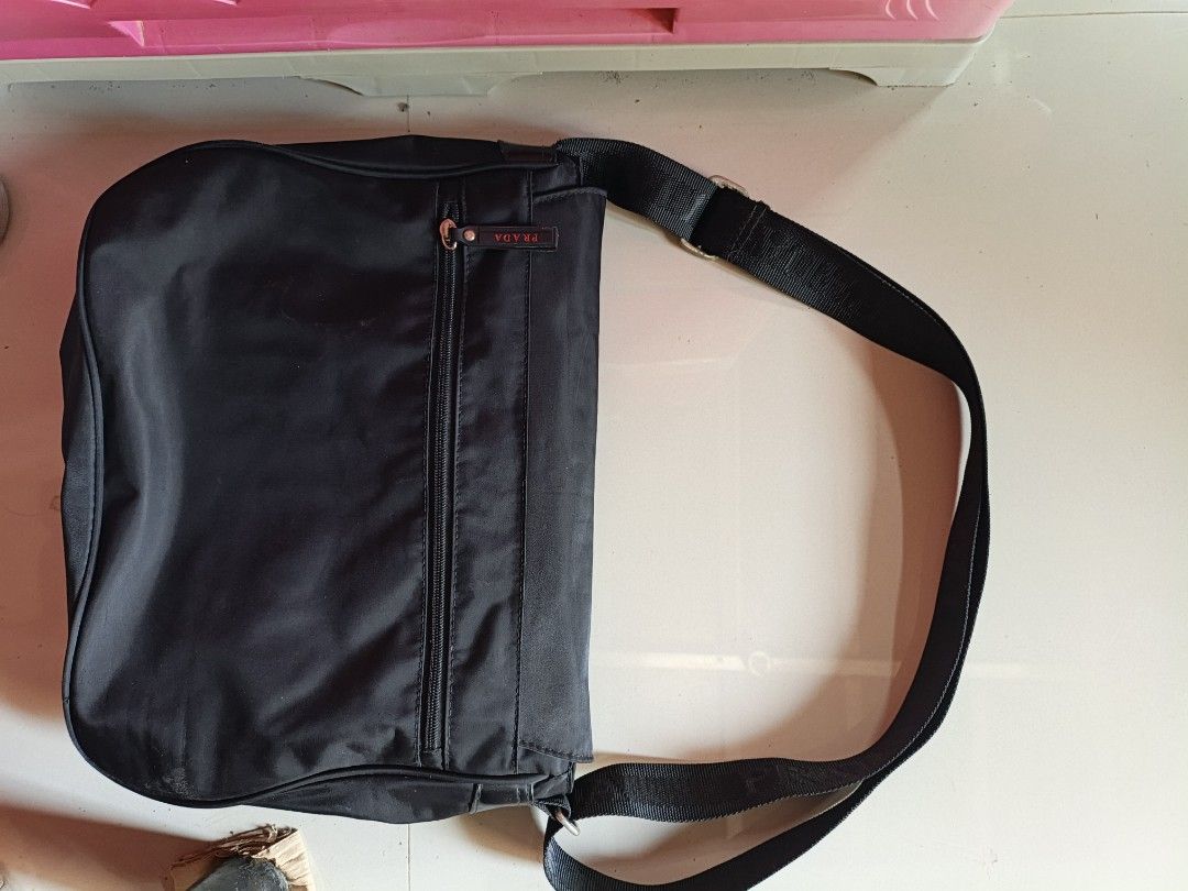 Prada Nylon Messenger Bag Black (Category: Luxury Bags & Wallets) located in Bambang. Submitted by acpalthrifts (Listing ID 1444114568, Image 2). Description: - Prada messenger bag - Black nylon material - Adjustable strap with Prada branding - Interior Prada Milano Made in Italy tag - Minor exterior wear on fabric and corners - Still functional and stylish for everyday use.