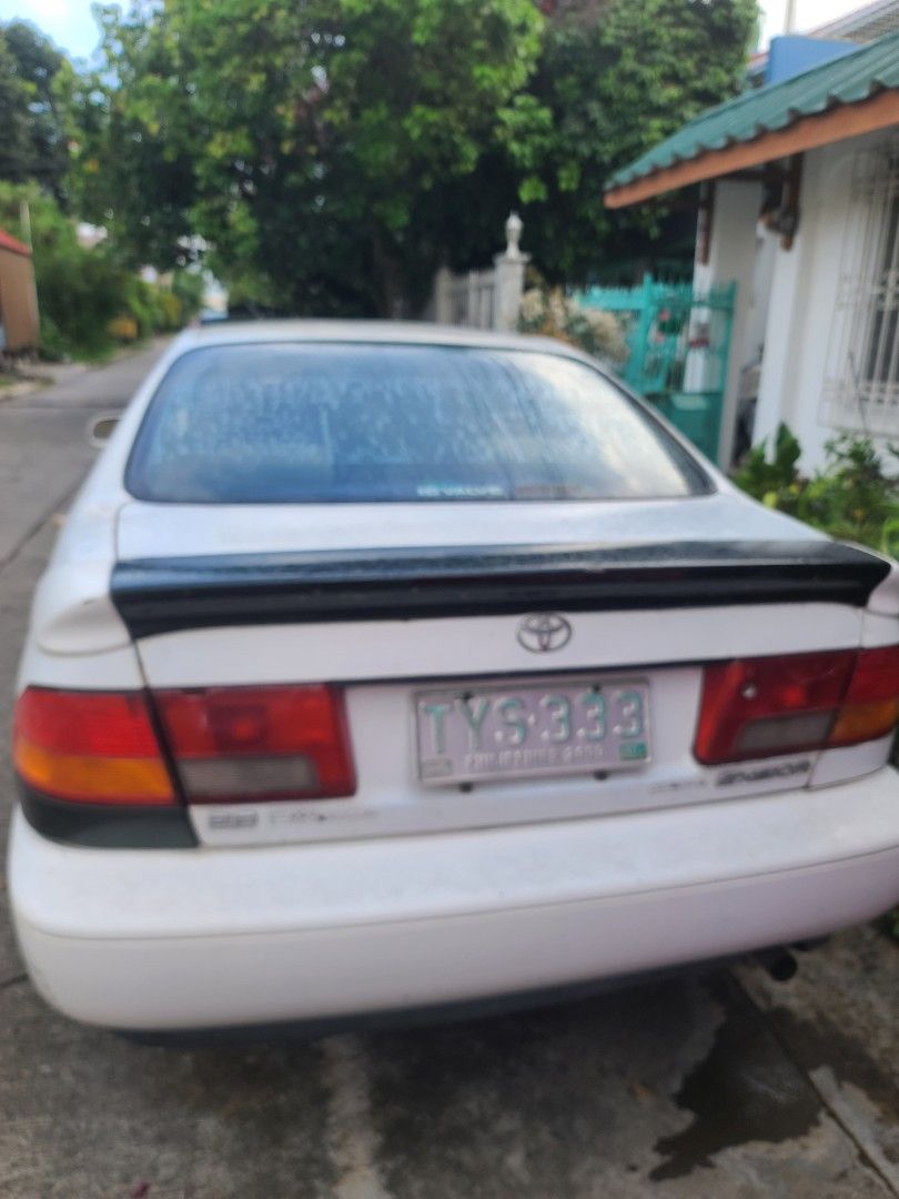Toyota Corona (Category: Used Cars) located in Quezon City. Submitted by veegee1216 (Listing ID 1444162997, Image 2). Description: Selling a white Toyota CORONA EXSIOR 1998 MODEL This car has a sporty look with a rear spoiler. Automatic transmission. License plate is visible in the photos. in running condition- cold AC NEWLY REPLACED BATTERY *NOT REGISTERED *1 passenger side AUTOMATIC WINDOWS NOT WORKING FREE TRINK MOUNTAIN BIKE STILL GOOD BUT GO
