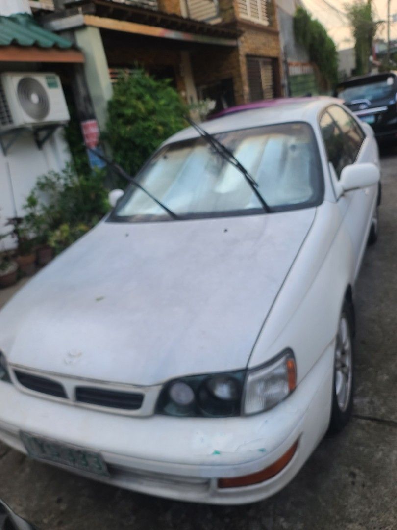 Toyota Corona (Category: Used Cars) located in Quezon City. Submitted by veegee1216 (Listing ID 1444162997, Image 1). Description: Selling a white Toyota CORONA EXSIOR 1998 MODEL This car has a sporty look with a rear spoiler. Automatic transmission. License plate is visible in the photos. in running condition- cold AC NEWLY REPLACED BATTERY *NOT REGISTERED *1 passenger side AUTOMATIC WINDOWS NOT WORKING FREE TRINK MOUNTAIN BIKE STILL GOOD BUT GO