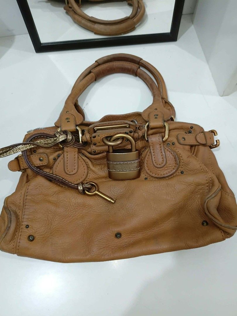 Authentic Chloe Paddington Satchel bag (Category: Luxury Bags & Wallets) located in Quezon City. Submitted by jäckpötjöy (Listing ID 1444344744, Image 1). Description: - Authentic Chloe Paddington bag - Color: Tan leather - Iconic padlock detail with key charm - Top handles - Zip closure - Fabric interior lining - Shows some signs of wear on leather and interior - A classic and timeless piece A well-preserved piece featuring beautifully aged leat