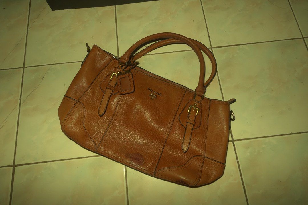 Prada Brown Leather Tote Bag (Category: Luxury Bags & Wallets) located in Manila. Submitted by noooneeee99 (Listing ID 1444406837, Image 1). Description: Bought it from Thailand for 7k. Prada bag. Made of brown pebbled leather. Has a spacious interior with a zip pocket. Gold hardware details. Some signs of wear on the bottom corners, as pictured. A classic everyday bag. Theres a water mark on the bottom. .