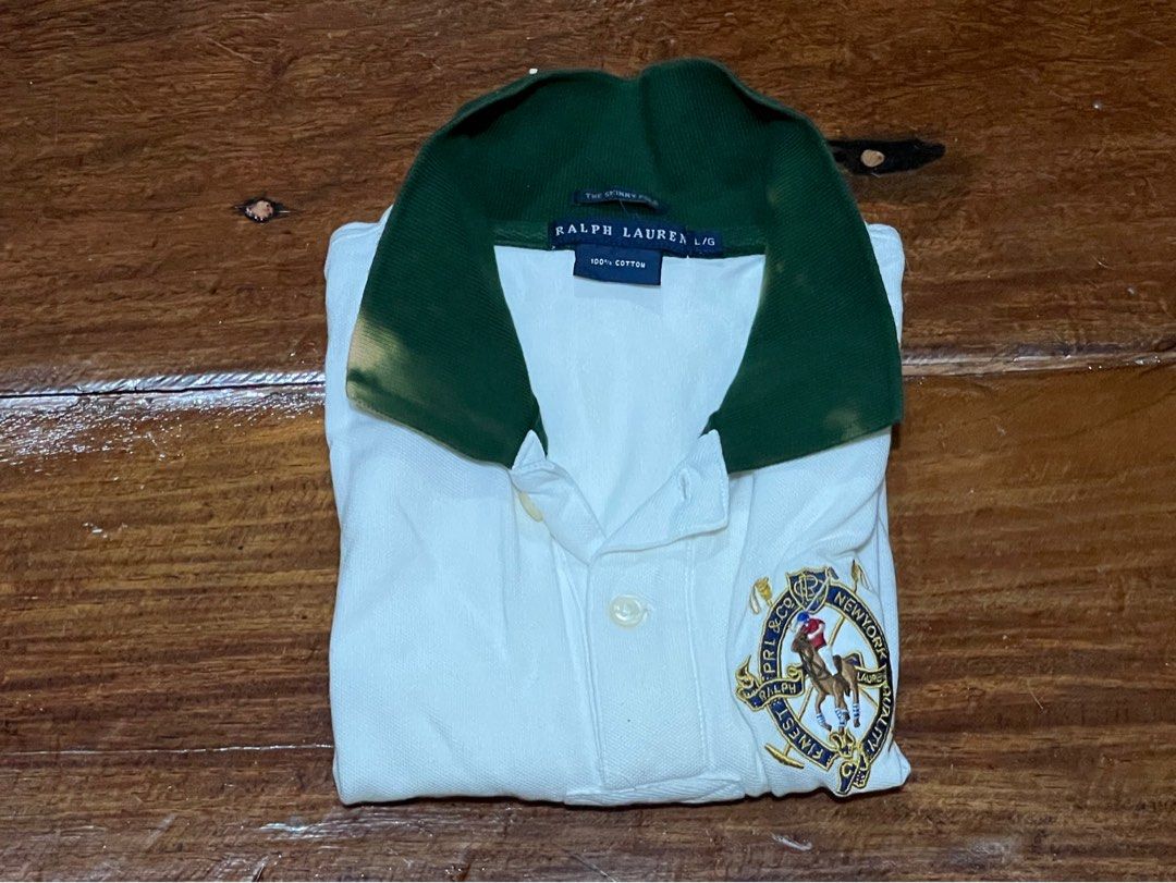 Ralph Lauren Polo Shirt (Category: Blouses) located in Leyte. Submitted by jcatle (Listing ID 1444362179, Image 3). Description: - Classic white Ralph Lauren polo shirt - Size: Large (L) on tag but fits xs-small - It has bleached stains on the collar. - Needs a wash - Short sleeves - Button-up neckline - Features iconic Ralph Lauren crest logo on chest - Green collar with minor discoloration - Material: 100% Cotton.