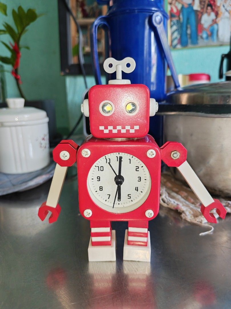 Red Wind-Up Robot Alarm Clock with Winding Key (Category: Clocks) located in Carmona. Submitted by tech_hub_cavite (Listing ID 1444370910, Image 1). Description: - Adorable red robot design alarm clock - Features a classic wind-up mechanism with key on top - Poseable arms for a fun, customizable look - Clear white clock face with easy-to-read black numbers and hands - Battery compartment located on the back - Ideal decorative piece for desks, she