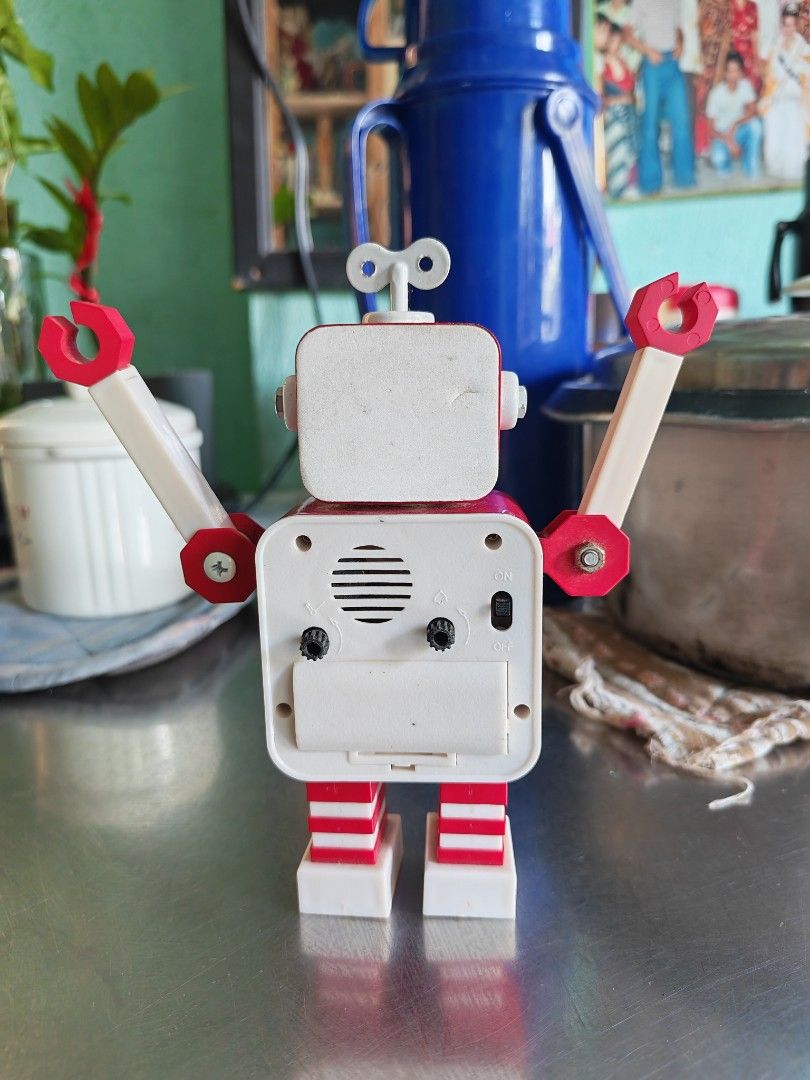 Red Wind-Up Robot Alarm Clock with Winding Key (Category: Clocks) located in Carmona. Submitted by tech_hub_cavite (Listing ID 1444370910, Image 3). Description: - Adorable red robot design alarm clock - Features a classic wind-up mechanism with key on top - Poseable arms for a fun, customizable look - Clear white clock face with easy-to-read black numbers and hands - Battery compartment located on the back - Ideal decorative piece for desks, she