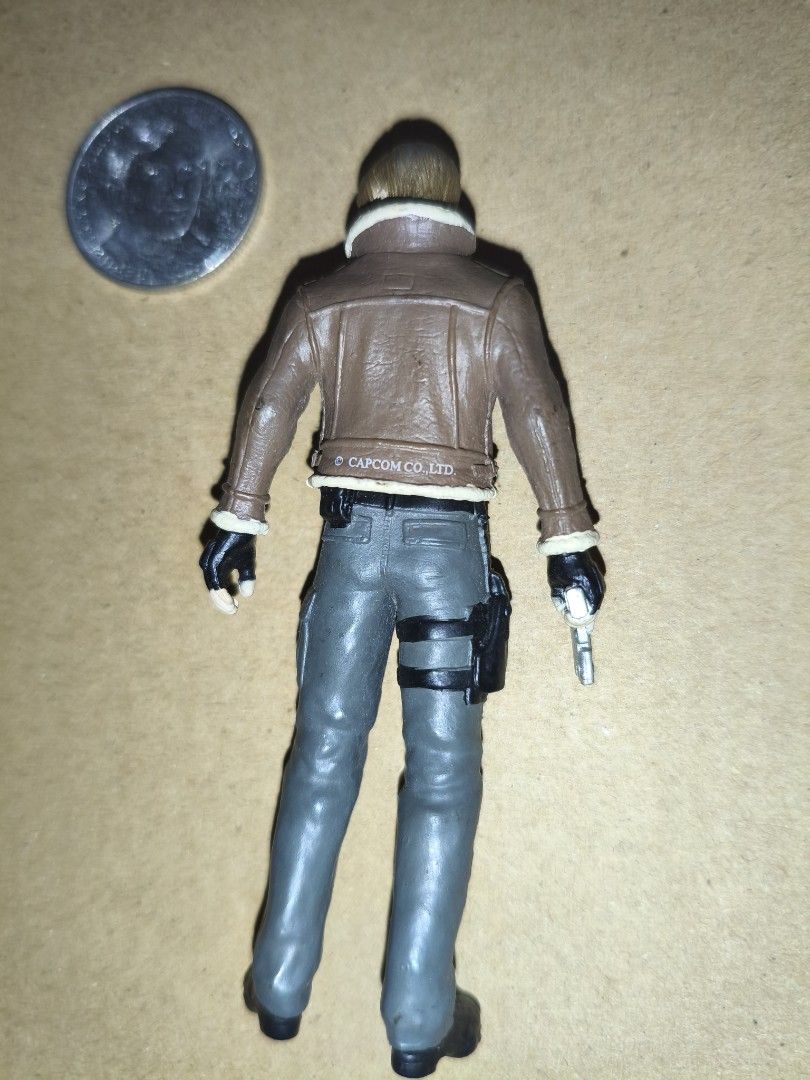 Resident Evil 4 Leon S. Kennedy Action Figure 3 inch (Category: Figurines & Statues) located in Manila. Submitted by v2Zuio (Listing ID 1444321933, Image 2). Description: - Resident Evil 4 Leon S. Kennedy action figure - Includes gun accessory and leg holster - Detailed outfit: brown jacket with fur collar, grey pants - Ideal collectible for Resident Evil enthusiasts - Approximately quarter-sized.
