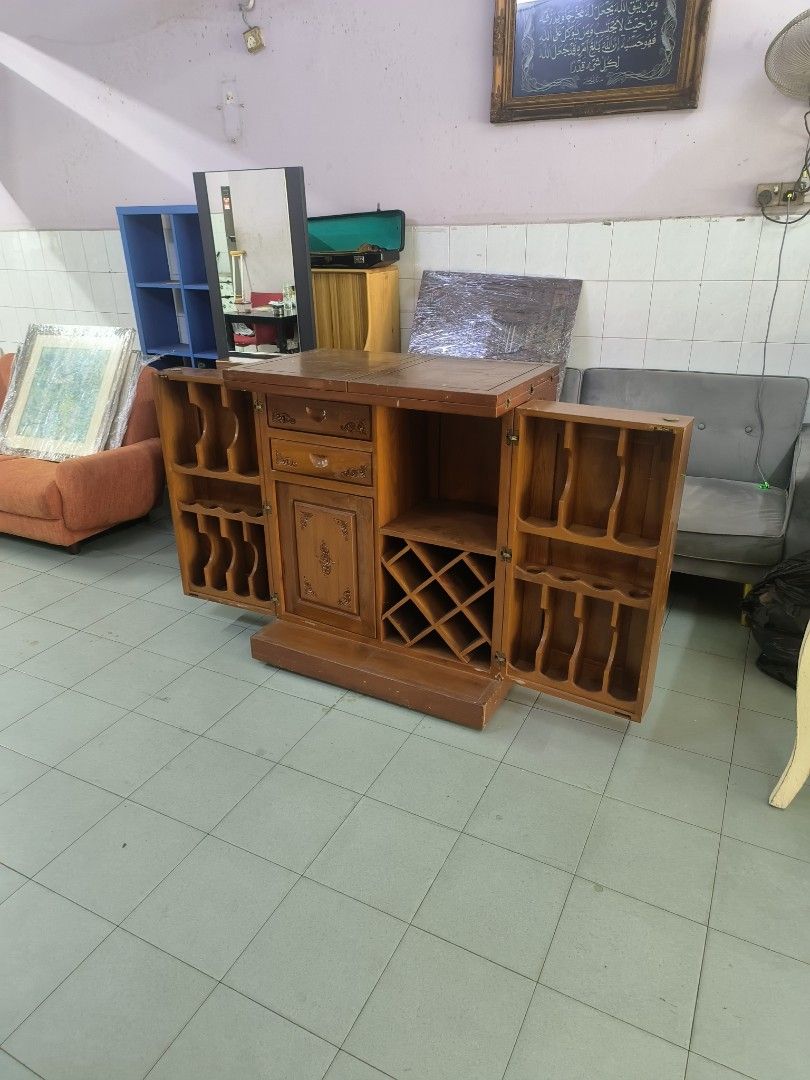 Wooden Bar Cabinet with Wine Rack and Storage (Category: Shelves, Cabinets & Racks) located in Johor Bahru. Submitted by borneobundle4 (Listing ID 1444345595, Image 3). Description: - kayu jati - Central wine rack - Ample side storage shelves - Includes a small drawer - Ideal for entertaining or home bar setup - Doors open fully for easy access - Features a warm, inviting wood tone.