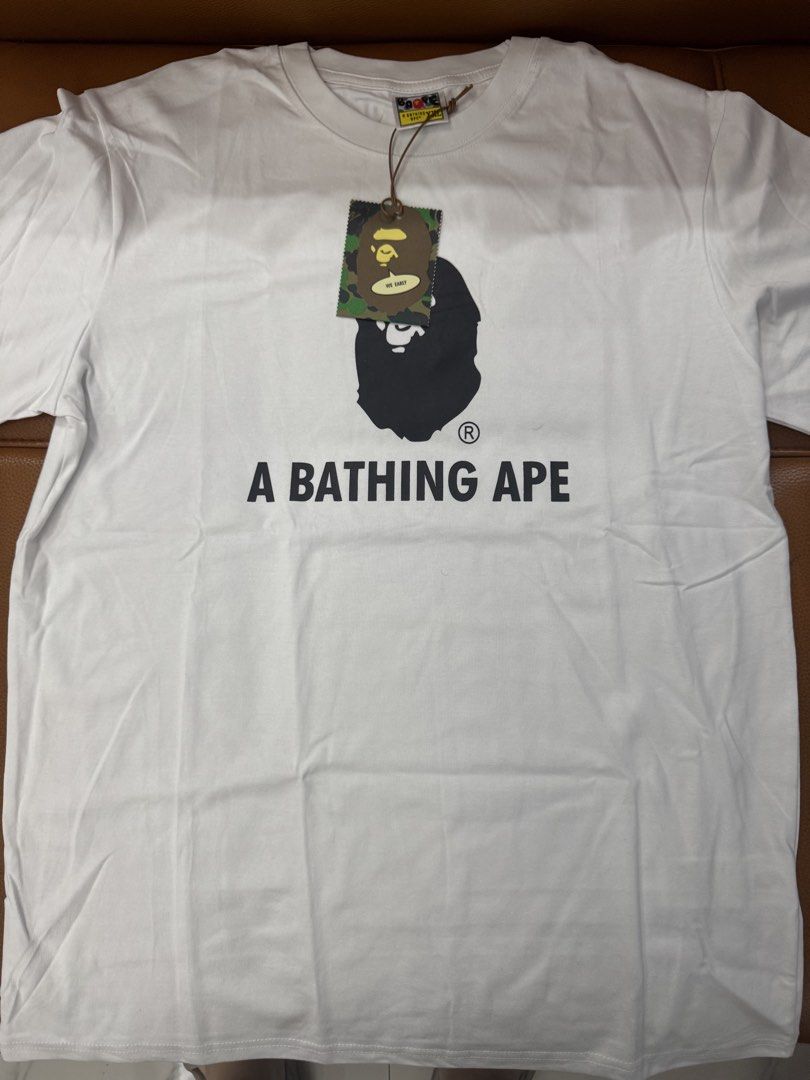 A Bathing Ape BAPE T-Shirt White (Category: Tshirts & Polo Shirts ) located in Manila. Submitted by mitchellzeng (Listing ID 1444501367, Image 1). Description: - Classic white BAPE t-shirt - Features iconic ape head graphic - Includes "A BATHING APE" text - Comes with original tags and packaging - Ideal for streetwear fans.