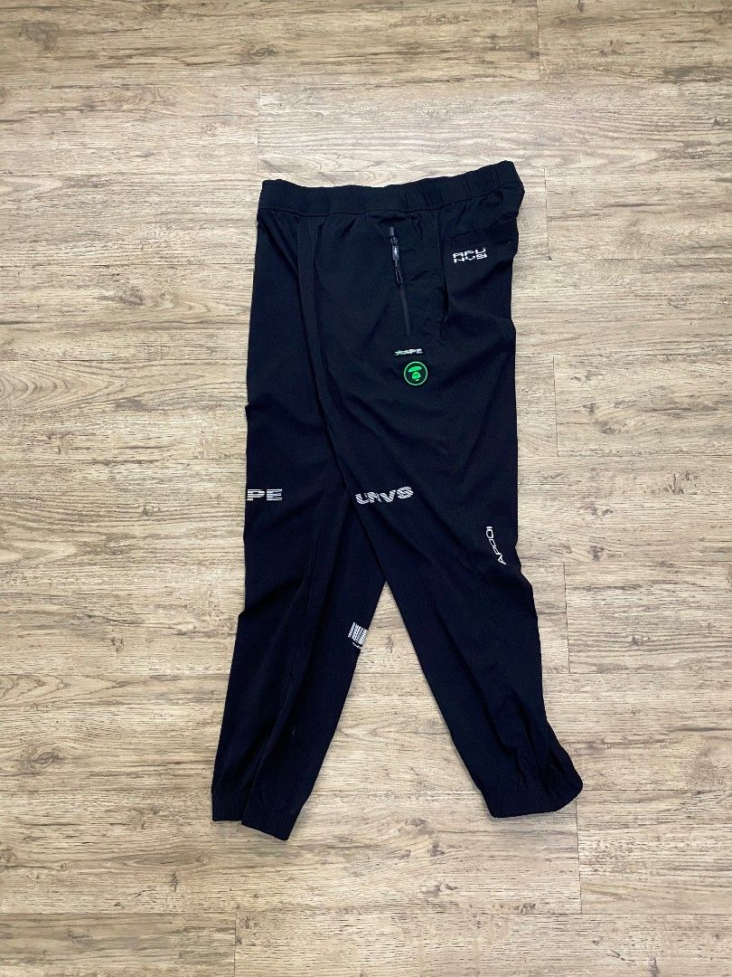 BAPE AP-201209 Black Track Pants (Category: Joggers) located in Cebu City. Submitted by francloset_1 (Listing ID 1444537709, Image 2). Description: - Authentic BAPE track pants - Features iconic ape head logo and "BAPE" text graphics - Comfortable elastic waistband with drawstring - Convenient zippered side pockets - Includes a back pocket detail - Ideal for casual outings or sports activities -Dimes W16 L 37.5 Ins 14 T12 H 6.