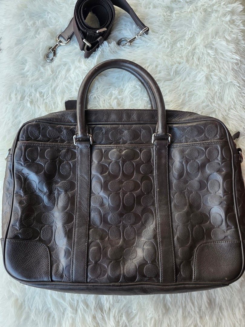 Coach Monogram Leather Briefcase Bag (Category: Briefcases) located in Lemery. Submitted by venus23 (Listing ID 1444679118, Image 2). Description: - Dark brown Coach monogram leather briefcase - Features signature Coach 'C' pattern embossed all over the leather - Includes top handles and a detachable shoulder strap - Sturdy design, ideal for work or travel - Shows some signs of wear on the handles and corners.