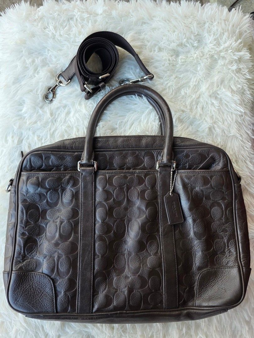 Coach Monogram Leather Briefcase Bag (Category: Briefcases) located in Lemery. Submitted by venus23 (Listing ID 1444679118, Image 1). Description: - Dark brown Coach monogram leather briefcase - Features signature Coach 'C' pattern embossed all over the leather - Includes top handles and a detachable shoulder strap - Sturdy design, ideal for work or travel - Shows some signs of wear on the handles and corners.