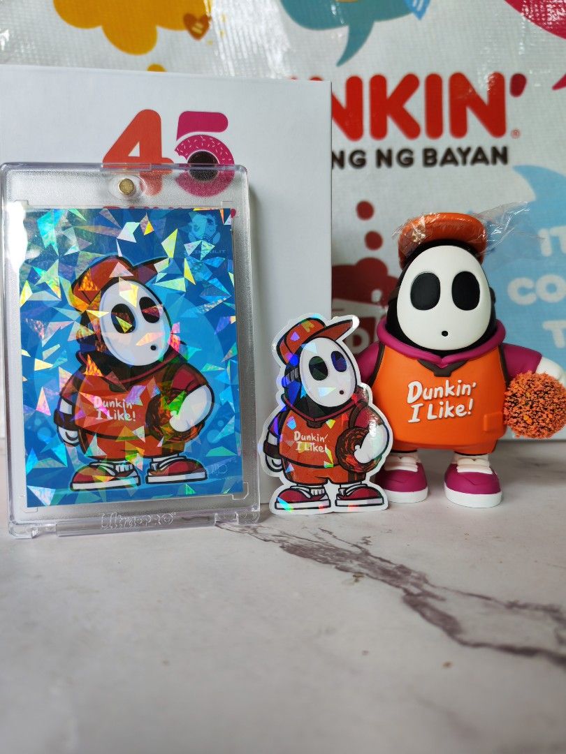 Dunkin Donut x EJ Sulit (Category: Designer & Blind Box Toys) located in Quezon City. Submitted by danilo.danilo4 (Listing ID 1444499867, Image 1). Description: - Adorable Shy Guy collectible set - Includes holographic card in protective case - Features 'Dunkin' I Like!' design on both items - Card has a sparkly, iridescent finish - Small figure is detailed and stands on its own - Ideal for collectors and fans of the character - Perfect for displ