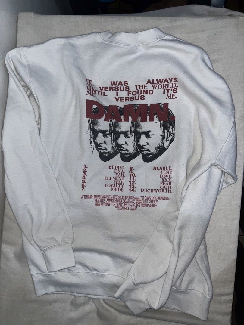Kendrick Lamar DAMN. Crewneck Sweatshirt (Category: Hoodies) located in Makati City. Submitted by gabrayco (Listing ID 1444618577, Image 3). Description: - White crewneck sweatshirt - Features Kendrick Lamar's DAMN. album art on the front - Back displays the DAMN. album tracklist and credits - Gildan Heavy Blend tag - Ideal for any Kendrick Lamar fan - dimes: Width(pit to pit) 21.5 inches length 26 inches very good condition.