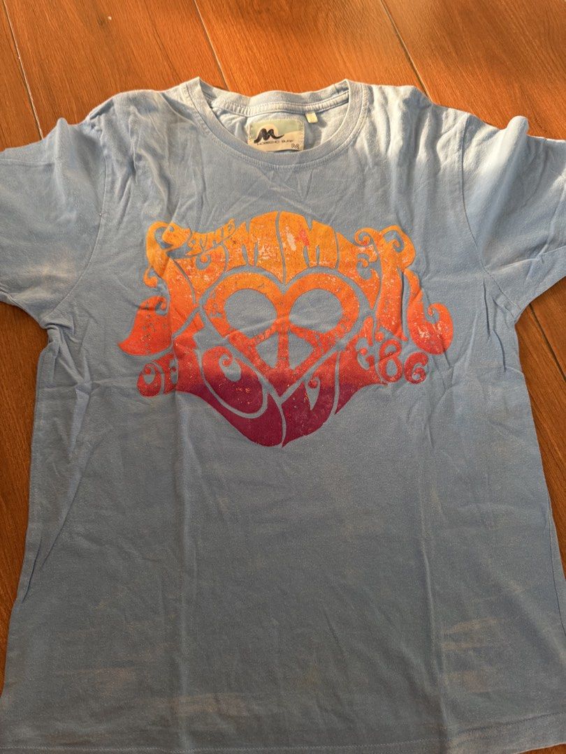 Mossimo Surf Blue T-shirt Size M (Category: Tshirts & Polo Shirts ) located in Bulacan. Submitted by emjay_17 (Listing ID 1444578787, Image 1). Description: - Brand: Mossimo Surf - Color: Light Blue - Size: Medium (M) - Design: Front graphic print featuring a peace sign and heart - Style: Casual wear.