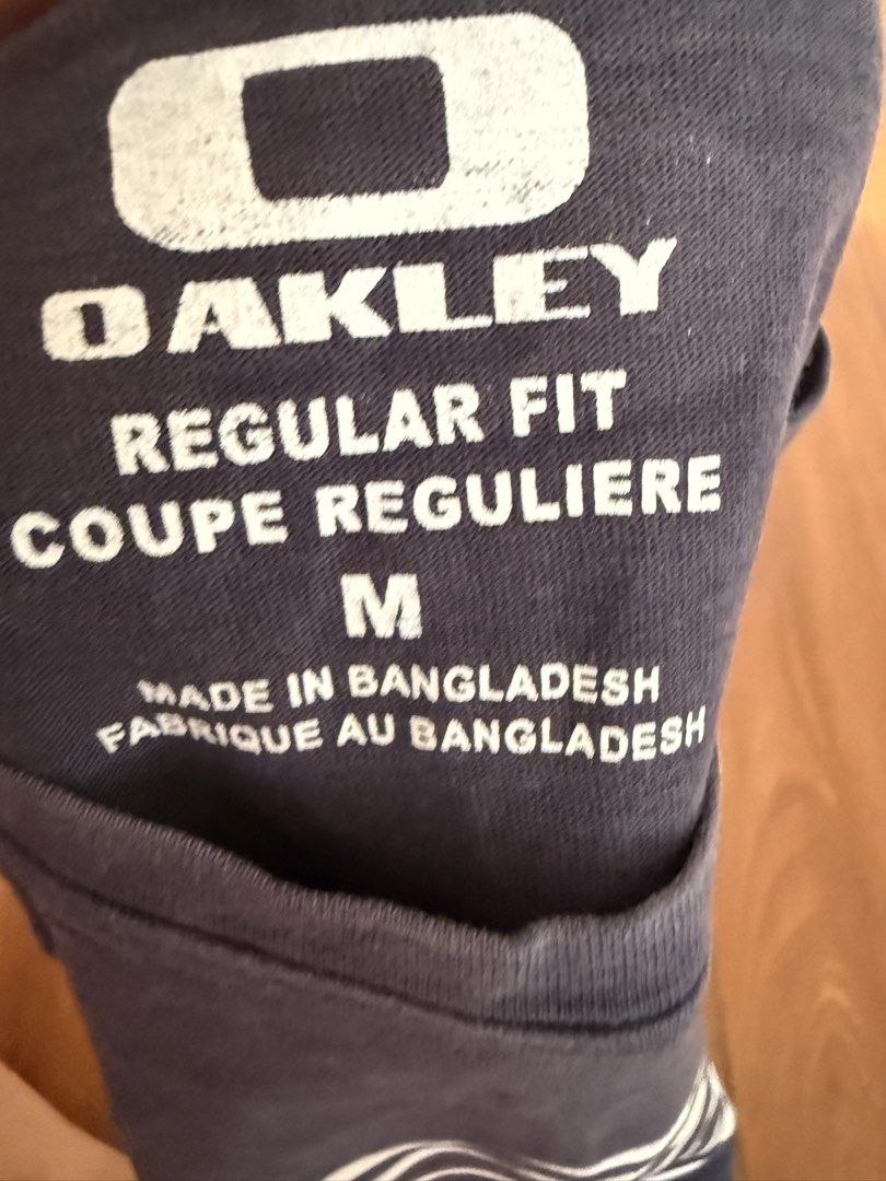 Oakley Regular Fit T-Shirt Size M (Category: Tshirts & Polo Shirts ) located in Bulacan. Submitted by emjay_17 (Listing ID 1444580414, Image 2). Description: - Navy blue Oakley t-shirt - Size: Medium (M) - Regular fit - Graphic logo on the front - Small Oakley logo on the back near the collar - Made in Bangladesh - Ideal for casual wear.