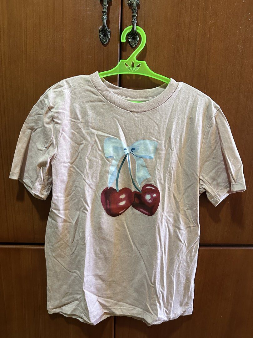 Pink T-shirt with Cherry Graphic (Category: Shirts) located in Dasmarinas. Submitted by maecybee (Listing ID 1444533824, Image 1). Description: - Adorable pink t-shirt - Features a cute cherry graphic and a sweet bow detail - Short sleeves and classic crew neck - Estimated size: Small to Medium - Made from soft, comfortable fabric - Ideal for everyday casual wear.