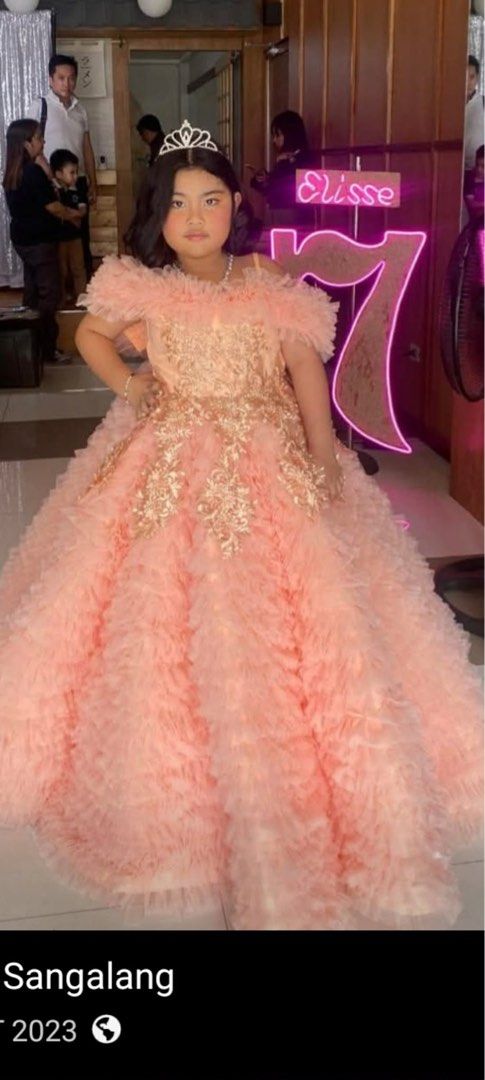 Princess Gown for 7th Birthday (Category: Babies & Kids Fashion) located in Makati City. Submitted by sebastiene (Listing ID 1444547858, Image 1). Description: - Beautiful peach gown with intricate gold embroidery. - Elegant off-the-shoulder design with delicate ruffled details. - Full, layered skirt also featuring ruffles for a princess-like flair. - Comes with a matching tiara, completing the magical look. - Ideal for special occasions such as 
