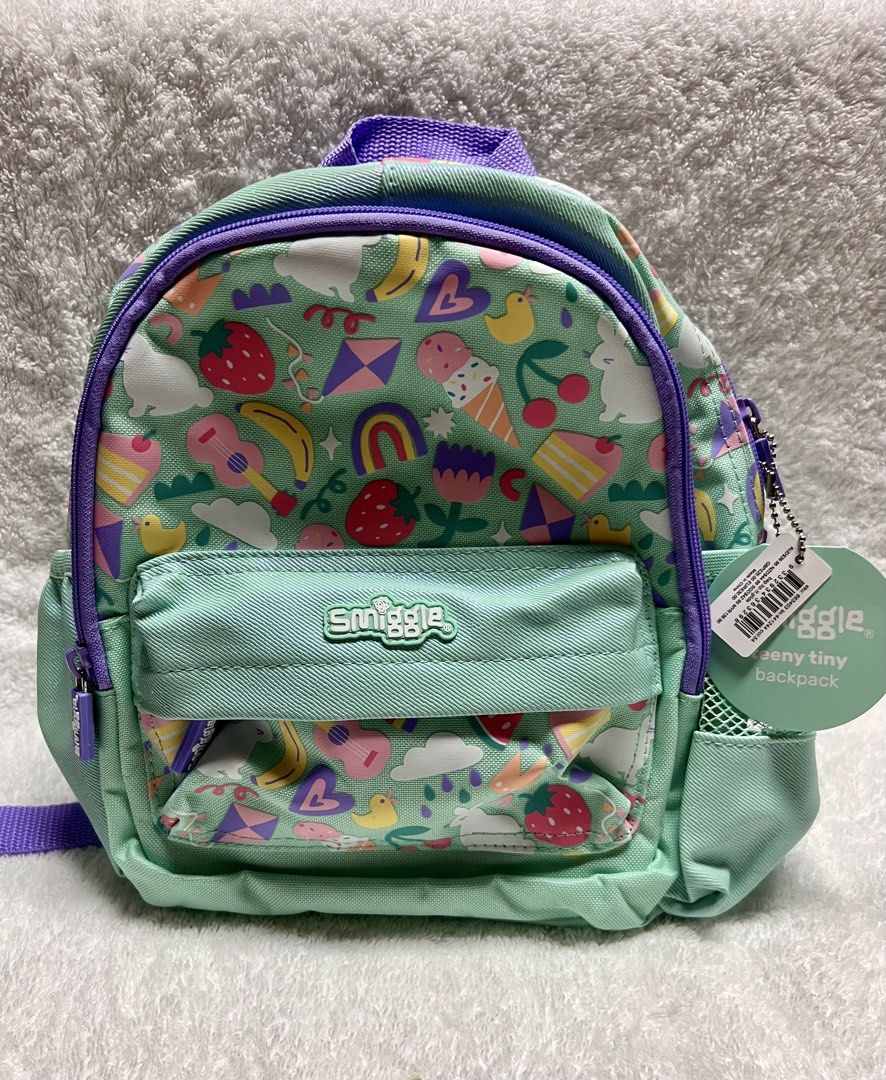 Smiggle Teeny Tiny Backpack - Fun Print (Category: Babies & Kids Fashion) located in Davao. Submitted by kbymonares (Listing ID 1444598506, Image 1). Description: - Adorable Smiggle backpack for little ones. - Fun, colorful print: fruits, ice cream, rainbows. - Color: Mint green with purple accents. - Features: Front pocket, mesh side pockets. - Adjustable straps for a comfy fit. - Ideal size for preschool or day trips..