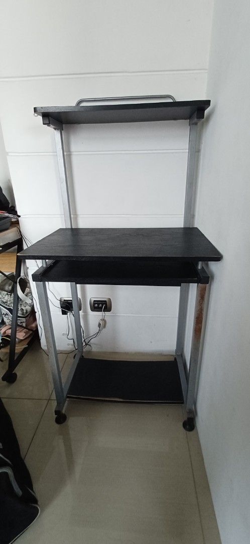 Computer table (Category: Shelves, Cabinets & Racks) located in Antipolo. Submitted by cone0812 (Listing ID 1444729269, Image 1). Description: - Two-tier rolling storage shelf - Black laminate surfaces - Sturdy metal frame - Convenient handle for easy moving - Wheels for effortless maneuverability - Some rust spots on metal frame (adds character!) - Ideal for organizing any space.