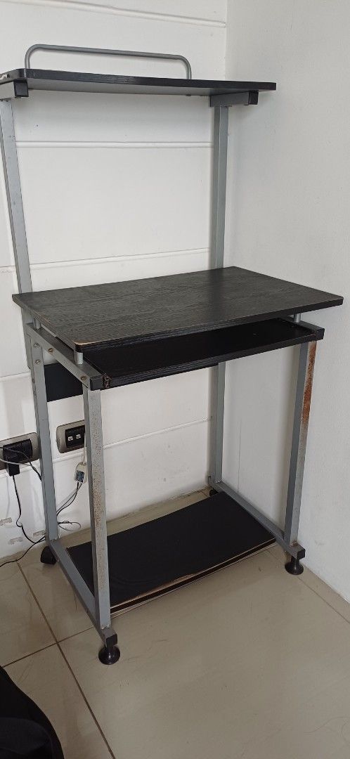 Computer table (Category: Shelves, Cabinets & Racks) located in Antipolo. Submitted by cone0812 (Listing ID 1444729269, Image 2). Description: - Two-tier rolling storage shelf - Black laminate surfaces - Sturdy metal frame - Convenient handle for easy moving - Wheels for effortless maneuverability - Some rust spots on metal frame (adds character!) - Ideal for organizing any space.
