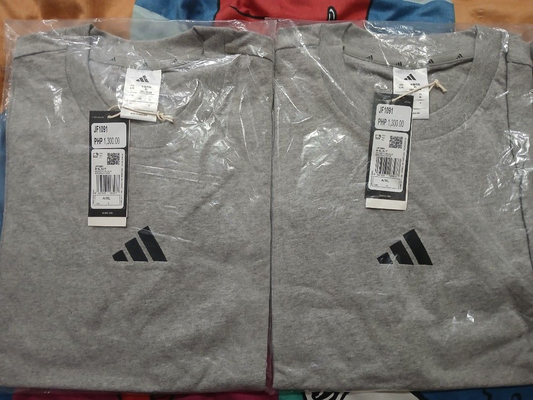 Adidas T-shirt Grey with Logo (Category: Tshirts & Polo Shirts ) located in Quezon City. Submitted by pompac25 (Listing ID 1444687795, Image 1). Description: - Brand new grey Adidas t-shirts - Still in original packaging - Features the classic Adidas logo on the front - Original price tag: PHP 1,300.00 - Ideal for casual and everyday wear.