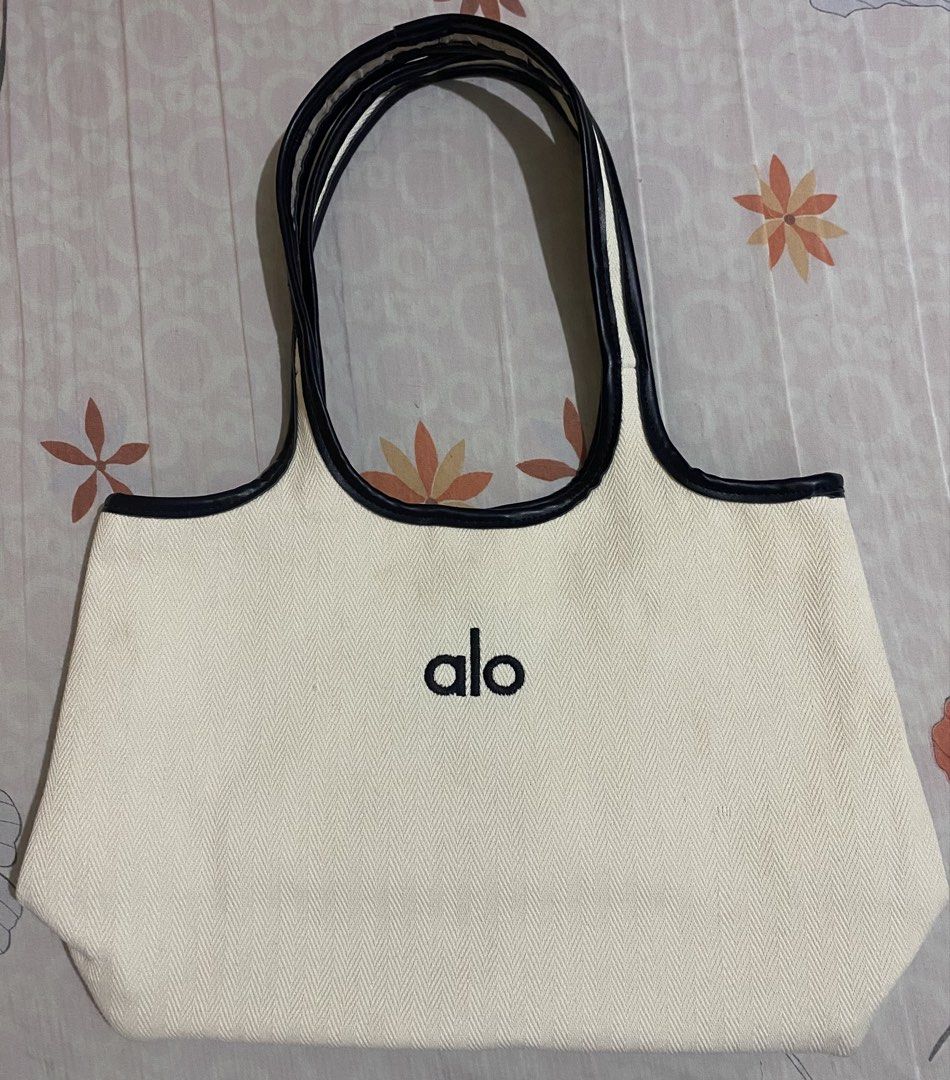 Alo Yoga Canvas Tote Bag (Category: Tote Bags) located in Lipa City. Submitted by bynina.ph (Listing ID 1444811911, Image 1). Description: Selling for v low ‼️issue: With color transfer stain sa likod (from black shirt) kaya pa malinis - AUTHENTIC - Black trim and handles - Embroidered Alo logo on front - Interior lining with repeating Alo Yoga print - Magnetic snap closure - Ideal for everyday use or gym trips.