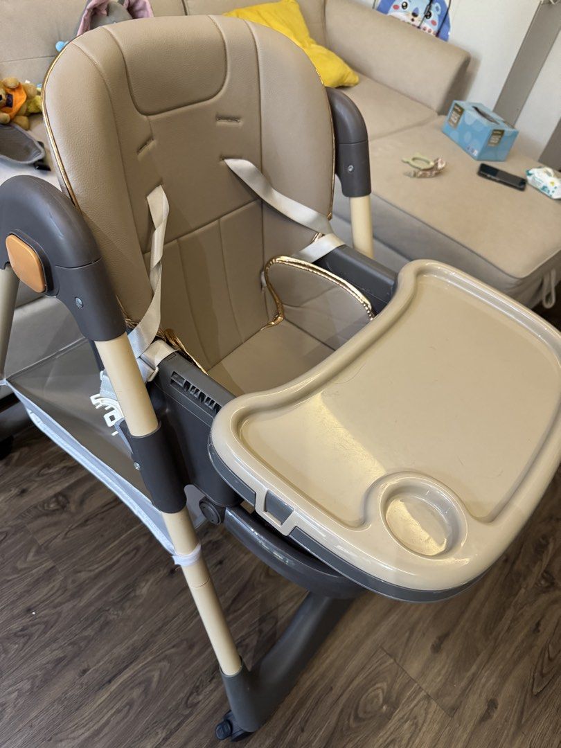 Baby High Chair with Tray and Footrest (Category: Baby High Chairs) located in Singapore. Submitted by hahask (Listing ID 1444856149, Image 3). Description: - Adjustable baby high chair - Removable tray - Footrest included - Safety harness for secure seating - Wheels for easy movement around the house - Neutral beige seat and tray - Light wood tone frame with grey accents - Ideal for meal times.