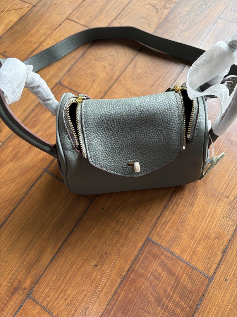 Designer Style Leather Handbag (Category: Luxury Bags & Wallets) located in Pasig City. Submitted by mvsdb (Listing ID 1444695627, Image 3). Description: - Grey pebbled leather handbag - Top handles and detachable shoulder strap - Elegant gold hardware details - Secure zip closure for the main compartment - Convenient small flap pocket on the front - Protective plastic still on some hardware - Ideal for everyday use.